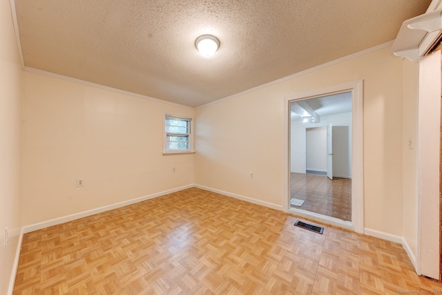 spare room with a textured ceiling, crown molding, and baseboards