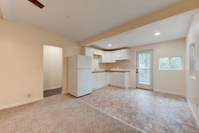 kitchen with freestanding refrigerator, under cabinet range hood, white cabinetry, recessed lighting, and baseboards