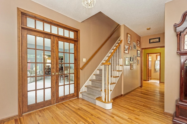 250 Wooding Hill Rd, Bethany, CT 06524 - foyer featuring french doors, light wood-style floors, stairway, a textured ceiling, and baseboards
