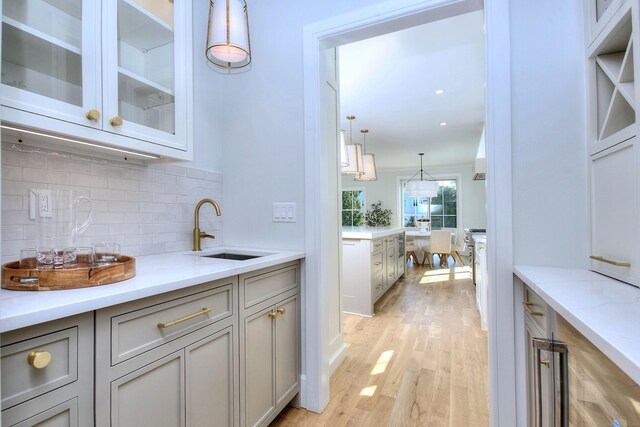 450 Penfield Rd, Fairfield, CT 06824 - bar featuring a sink, backsplash, light wood-style floors, and hanging light fixtures