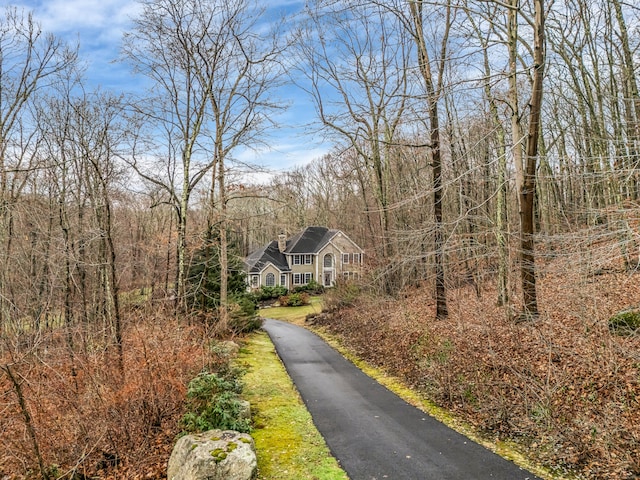 view of asphalt driveway with a view of trees