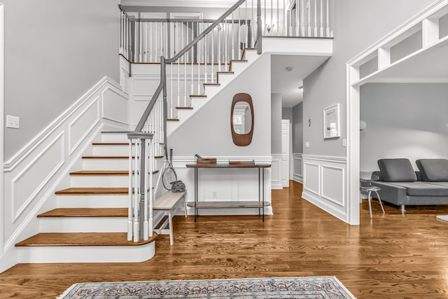 38 Marlin Rd, Newtown, CT 06482 - stairs featuring a towering ceiling, wood finished floors, a decorative wall, and wainscoting