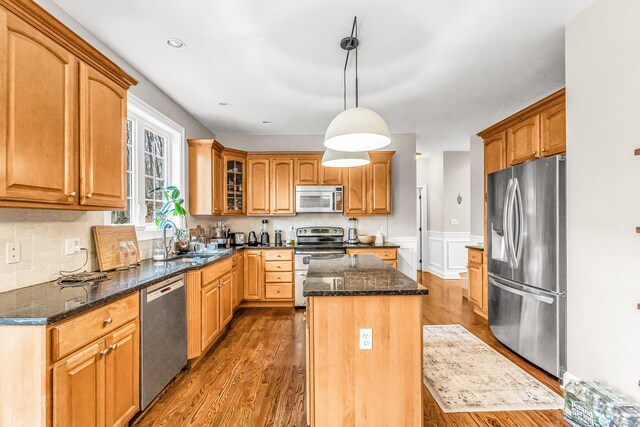 38 Marlin Rd, Newtown, CT 06482 - kitchen with appliances with stainless steel finishes, a center island, wood finished floors, dark stone countertops, and wainscoting