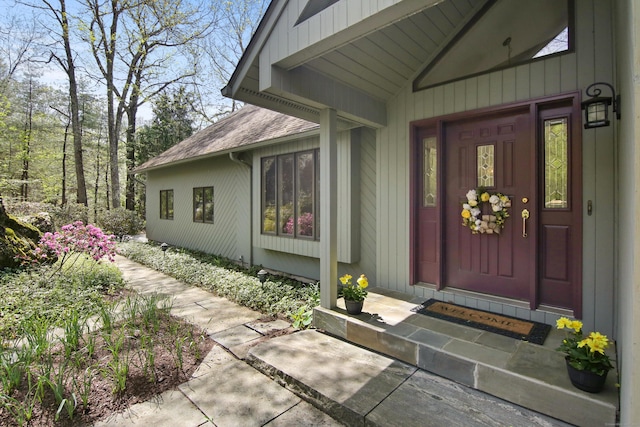 view of exterior entry featuring a shingled roof