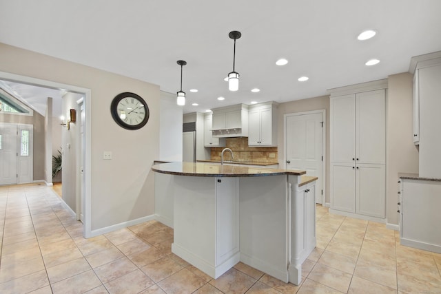 kitchen with backsplash, dark stone counters, recessed lighting, light tile patterned floors, and under cabinet range hood