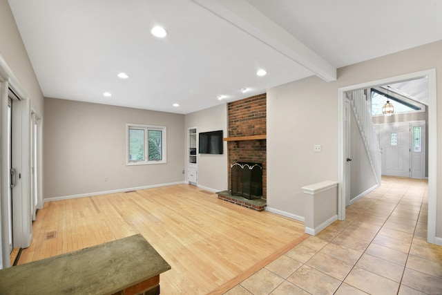 unfurnished living room featuring a brick fireplace, light wood-type flooring, recessed lighting, baseboards, and beam ceiling