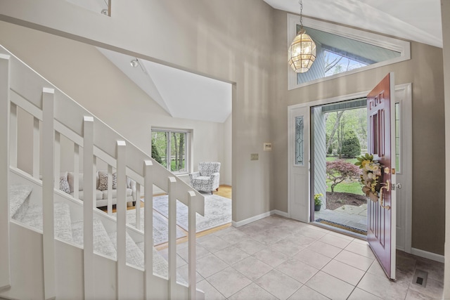 entrance foyer featuring healthy amount of natural light, baseboards, a chandelier, and high vaulted ceiling