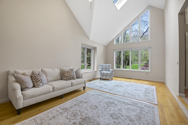living area with high vaulted ceiling, light wood finished floors, and baseboards