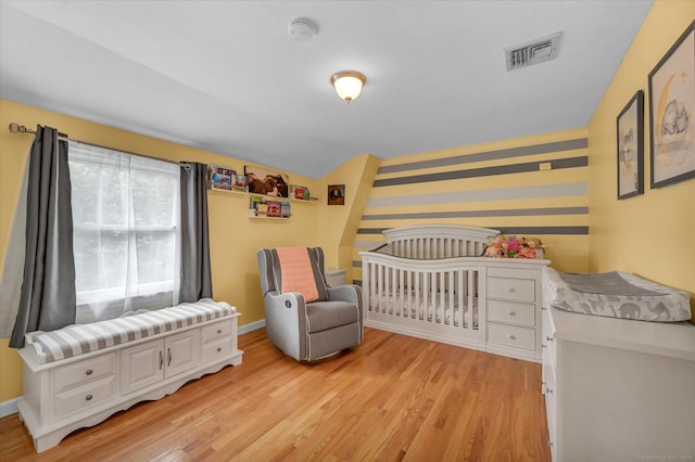 7 Beechwood Cir, Cromwell, CT 06416 - bedroom with wallpapered walls, light wood-type flooring, baseboards, a crib, and an accent wall