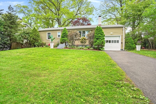 view of front facade featuring a garage, a chimney, driveway, and a front yard