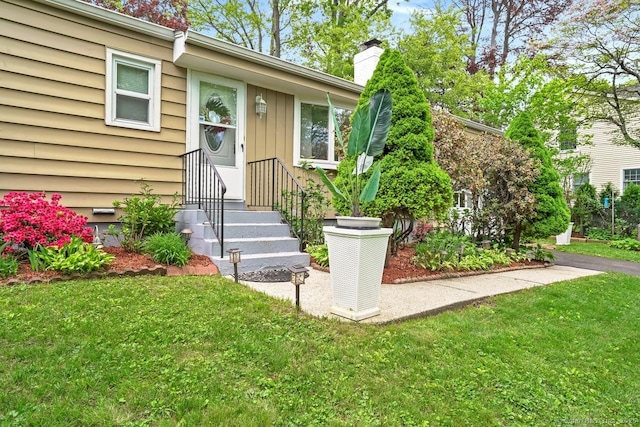 entrance to property featuring a yard and a chimney