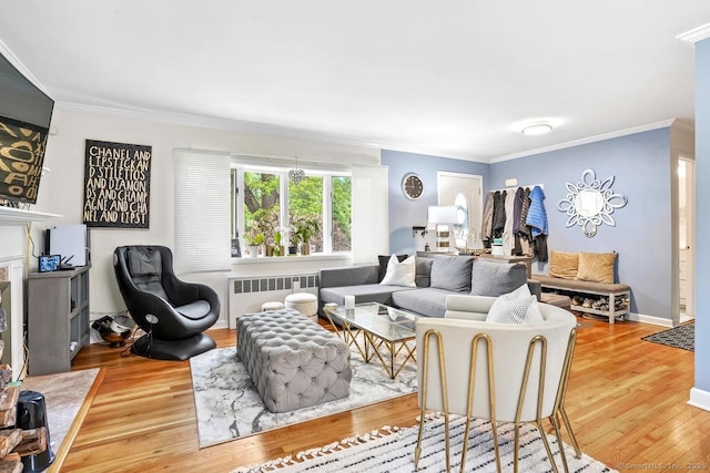living room with radiator heating unit, wood finished floors, ornamental molding, and baseboards