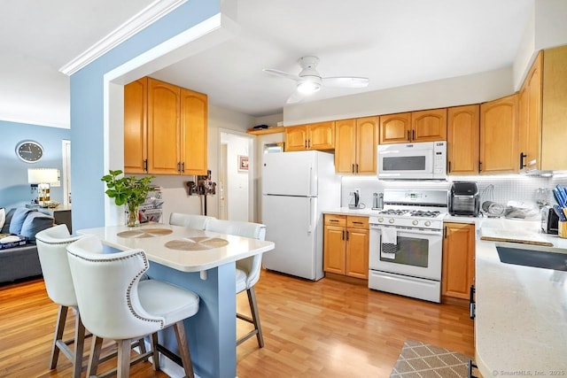 kitchen with white appliances, a breakfast bar, decorative backsplash, a peninsula, and light countertops