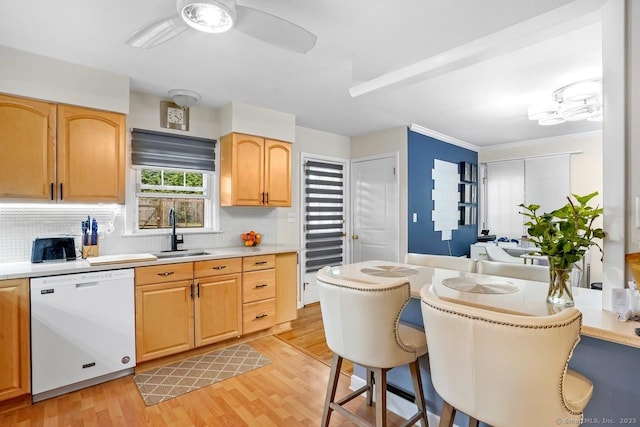 kitchen featuring white dishwasher, a sink, backsplash, and light countertops