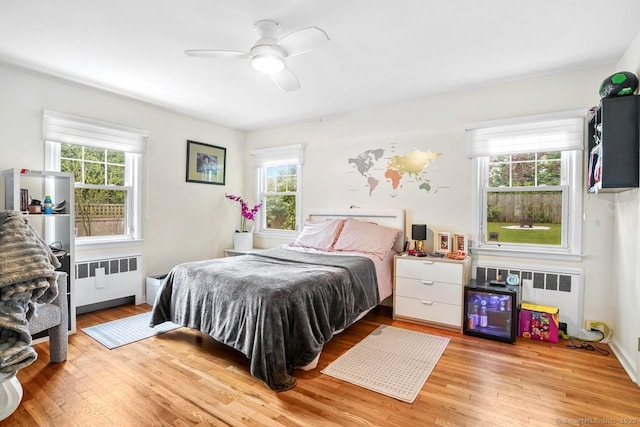 bedroom with radiator, multiple windows, and wood finished floors