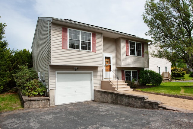 split foyer home featuring an attached garage and asphalt driveway