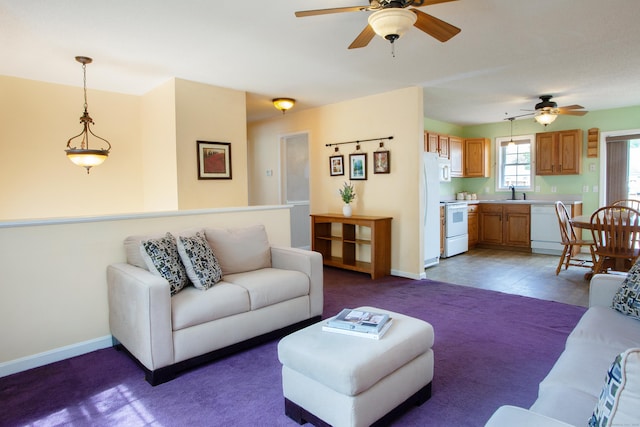 living area with ceiling fan, baseboards, and carpet floors