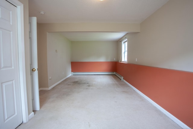 empty room featuring carpet floors, baseboards, a baseboard heating unit, and a smoke detector