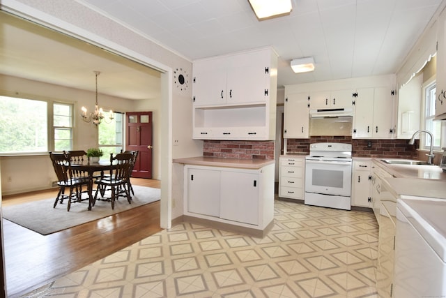 12 Cedar Ln, Oxford, CT 06478 - kitchen with electric stove, a sink, under cabinet range hood, a chandelier, and white cabinets