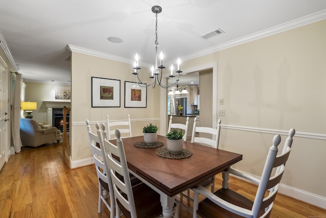 79 Erdoni Rd, Columbia, CT 06237 - dining space featuring ornamental molding, light wood-type flooring, a chandelier, a lit fireplace, and baseboards