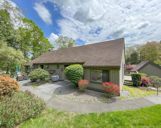 rear view of house featuring roof with shingles, a wooden deck, and central air condition unit