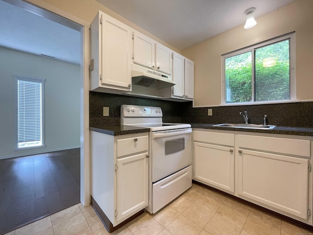 kitchen featuring white electric range, a sink, under cabinet range hood, white cabinetry, and dark countertops
