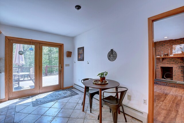 7 Stonegate Rd, East Hampton, CT 06424 - dining space with a baseboard radiator, baseboards, stone tile floors, and a brick fireplace