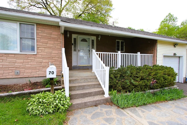 view of front of house with stone siding, covered porch, and an attached garage