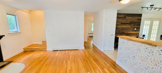 unfurnished room featuring a baseboard radiator, light wood finished floors, radiator heating unit, a smoke detector, and baseboards