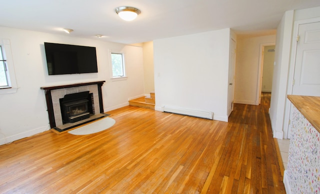 unfurnished living room featuring a baseboard heating unit, hardwood / wood-style flooring, and baseboards