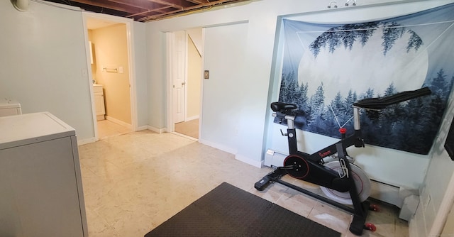 exercise area featuring washer / clothes dryer, baseboard heating, and baseboards