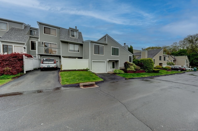 view of property with driveway, an attached garage, a residential view, and roof with shingles