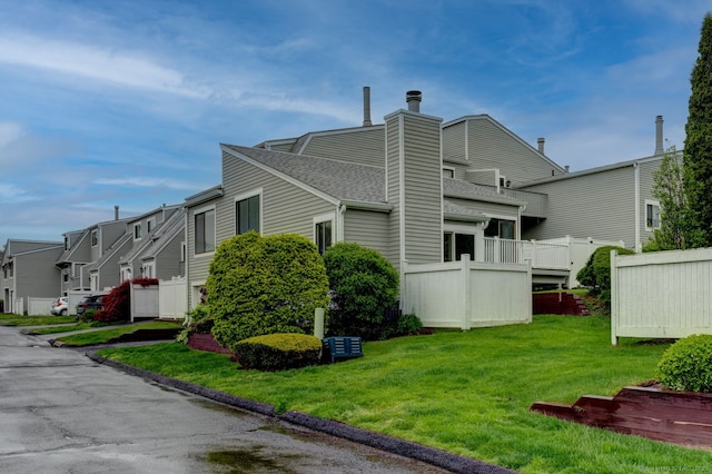 view of side of property with a residential view, a chimney, roof with shingles, and a lawn