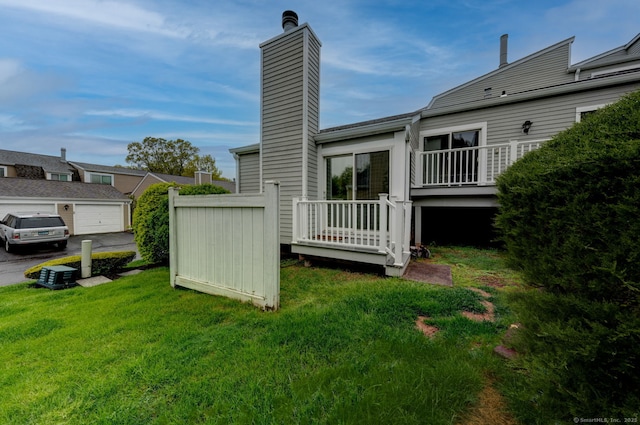 back of house featuring a chimney and a lawn