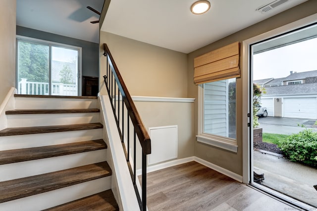 stairway with wood finished floors, a ceiling fan, and baseboards