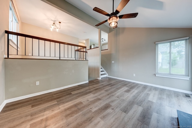 unfurnished room featuring vaulted ceiling, ceiling fan, wood finished floors, stairway, and baseboards