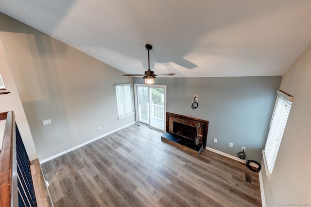 unfurnished living room with a fireplace, a ceiling fan, wood finished floors, baseboards, and lofted ceiling