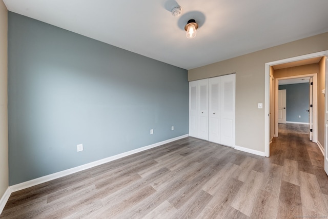 unfurnished bedroom with wood finished floors, a closet, and baseboards
