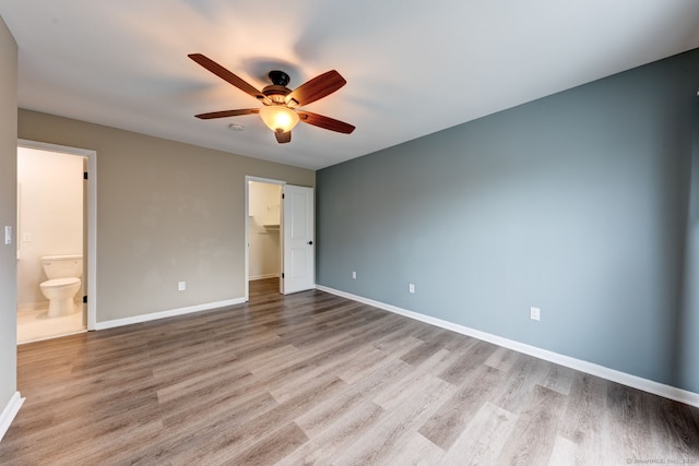 unfurnished bedroom with light wood-style flooring, a spacious closet, and baseboards