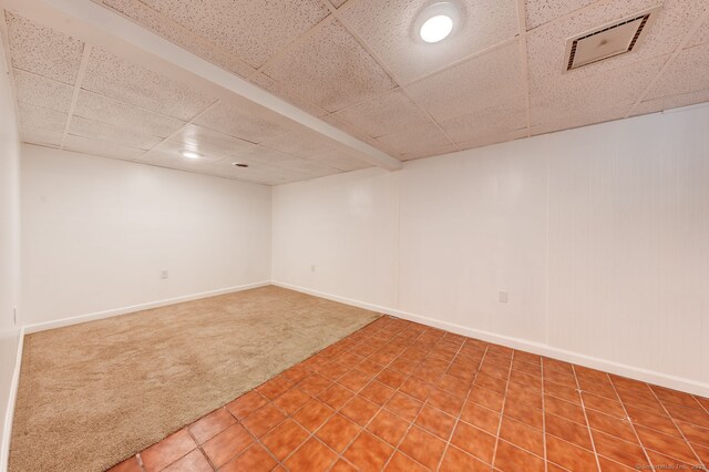 finished below grade area with carpet floors, a paneled ceiling, baseboards, recessed lighting, and tile patterned floors