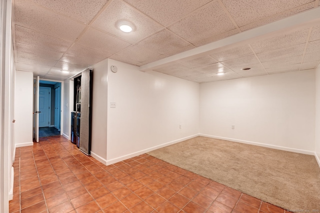 finished basement with light colored carpet, a drop ceiling, baseboards, and light tile patterned floors