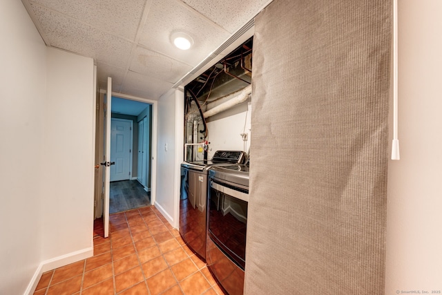 kitchen featuring washing machine and dryer, light tile patterned floors, and baseboards