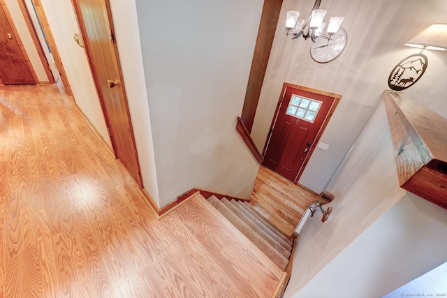 entryway with light wood-type flooring, a chandelier, baseboards, and stairway