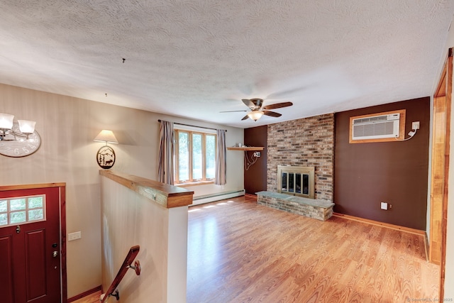 unfurnished living room with a baseboard radiator, ceiling fan, light wood finished floors, an AC wall unit, and a textured ceiling
