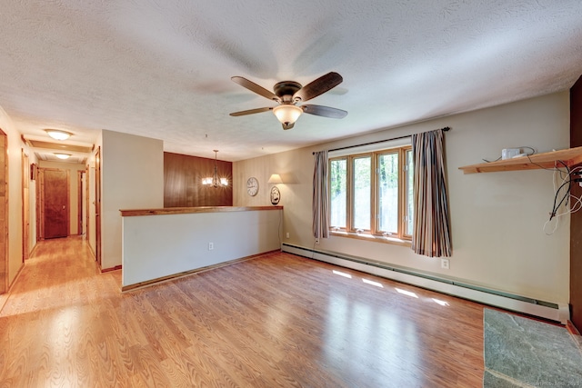 spare room featuring a baseboard radiator, light wood-type flooring, a ceiling fan, a textured ceiling, and baseboards