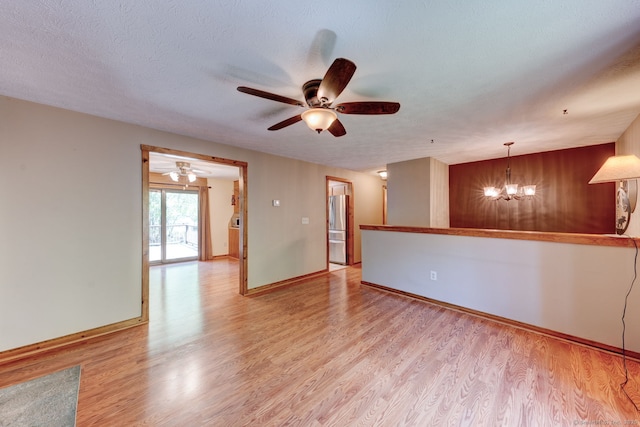 empty room with a ceiling fan, light wood-style floors, a chandelier, and baseboards