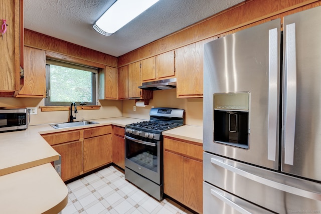 kitchen with stainless steel appliances, a sink, under cabinet range hood, light floors, and light countertops