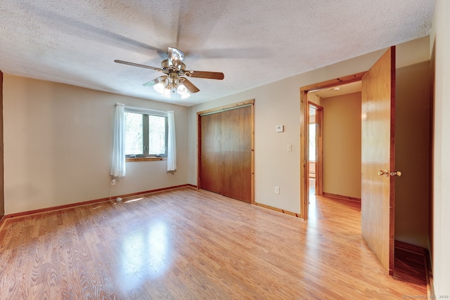 unfurnished bedroom featuring light wood-style floors, a textured ceiling, a closet, a ceiling fan, and baseboards