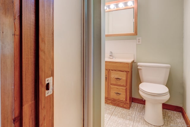 half bathroom with toilet, vanity, and tile patterned flooring
