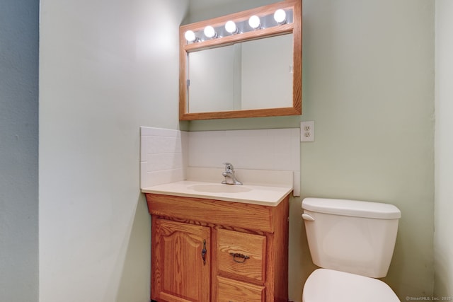 half bath with decorative backsplash, toilet, and vanity